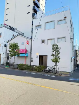 a white building with a bike parked next to a street at \u6d45\u8349\u99c5\u5f92\u6b698\u5206 \u6d45\u8349\u5bfa\u3059\u3050\u305d\u3070\u306e\u4ef2\u898b\u4e16\u6563\u7b56\u30b9\u30c6\u30a4 DqcYoE in Tokyo