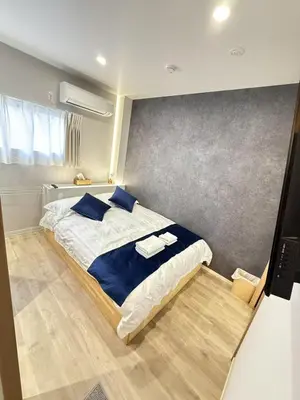 a bedroom with a large bed with blue pillows at \u6d45\u8349\u99c5\u5f92\u6b698\u5206 \u6d45\u8349\u5bfa\u3059\u3050\u305d\u3070\u306e\u4ef2\u898b\u4e16\u6563\u7b56\u30b9\u30c6\u30a4 DqcYoE in Tokyo