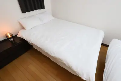 a bedroom with a white bed and a wooden floor at Omorinishi 3chome House in Tokyo
