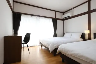 a bedroom with two beds and a chair and a window at Omorinishi 3chome House in Tokyo
