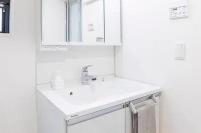 a white bathroom with a sink and a mirror at Akabanenishi 3chome House in Tokyo