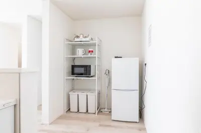 a white kitchen with a refrigerator and a microwave at Akabanenishi 3chome House in Tokyo
