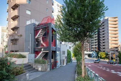 a building with a red balcony on the side of a street at Tomihisa House in Tokyo