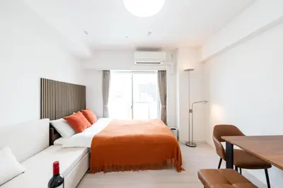 a bedroom with a couch and a bed with an orange blanket at LIVCITY Kinshicho 1101 Skytree view in Tokyo