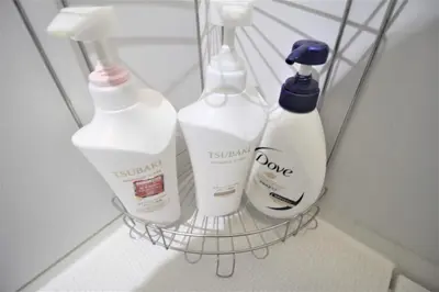a rack with three bottles of toiletries in a bathroom at MW Hotel in Tokyo