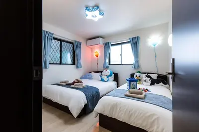 two beds in a bedroom with blue curtains at \u304b\u307e\u3082\u30551 in Tokyo