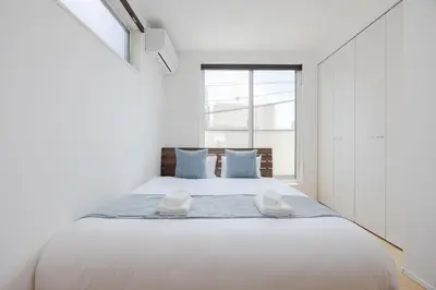a white bedroom with a large bed with blue pillows at First Choice Minami Kamata in Tokyo
