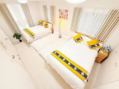 two beds in a room with white and yellow pillows at \u5409\u5c4b2\u53f7\u9928 in Tokyo