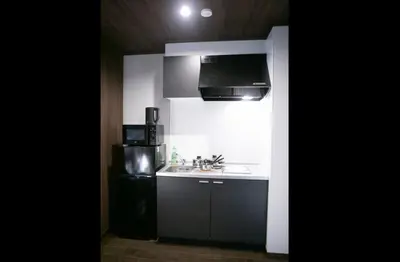 a kitchen with a sink and a black refrigerator at S-rea TOKYO in Tokyo