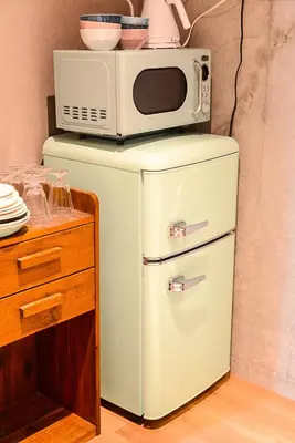 a microwave sitting on top of a refrigerator at \u539f\u7530\u5c4b Hotel 2F in Tokyo