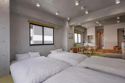 a room with four beds in it with a table at \u539f\u7530\u5c4b Hotel 7F in Tokyo