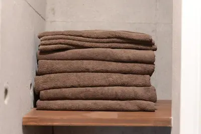 a stack of towels sitting on a wooden shelf at \u539f\u7530\u5c4b Hotel8F in Tokyo