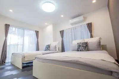 a bedroom with two beds and a window at \u5927\u4e45\u4fdd\u30b3\u30ea\u30a2\u30f3\u30bf\u30a6\u30f3\u76f4\u901a \u5317\u65b0\u5bbf\u306e\u30e2\u30c0\u30f3\u30b2\u30b9\u30c8\u30cf\u30a6\u30b9 YoYi in Tokyo