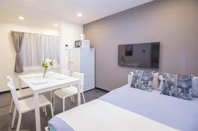 a room with a bed and a table and a refrigerator at \u5927\u4e45\u4fdd\u30b3\u30ea\u30a2\u30f3\u30bf\u30a6\u30f3\u76f4\u901a \u5317\u65b0\u5bbf\u306e\u30e2\u30c0\u30f3\u30b2\u30b9\u30c8\u30cf\u30a6\u30b9 YoYi in Tokyo