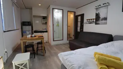 a living room with a bed and a table and a kitchen at Green house Japan in Tokyo