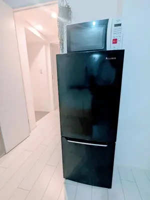 a microwave sitting on top of a black refrigerator at The Tokyo Okubo Shinjuku Homestay in Tokyo