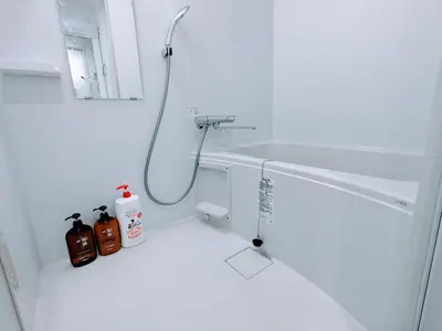 a white bathroom with a shower with a hose at The Tokyo Okubo Shinjuku Homestay in Tokyo