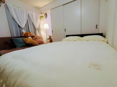 a bedroom with a large white bed with a teddy bear on it at The Tokyo Okubo Shinjuku Homestay in Tokyo