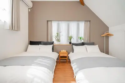 two twin beds in a room with a window at Kei House Shin-Okubo in Tokyo
