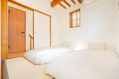 a bedroom with two beds and a door at Kei House Shin-Okubo in Tokyo