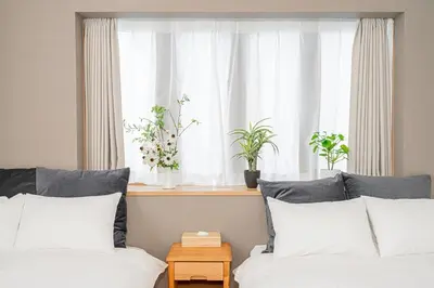 a bedroom with two beds and a window with plants at Kei House Shin-Okubo in Tokyo