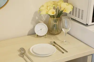 a table with a plate and a vase with yellow flowers at \u30d5\u30e9\u30c3\u30c8\u5409\u6751 202 in Tokyo