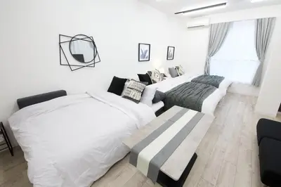 two beds and a couch in a white room at Oliver 502 in Tokyo
