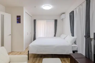 a white bedroom with a bed and a couch at Shibuyahonmachi 1F in Tokyo
