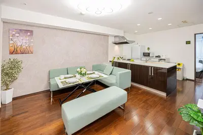 a living room with a table and chairs and a kitchen at Fukuei Stay Premium in Tokyo