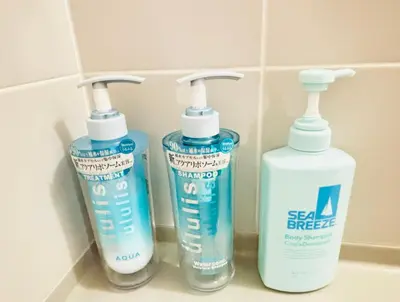 three bottles of cleaning products sitting on a bathroom sink at sunflower house in Tokyo