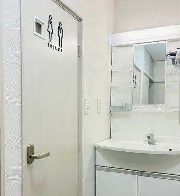 a bathroom with a sink and a door with a toilet sign at sunflower house in Tokyo