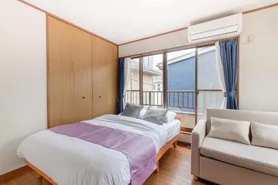 a bedroom with a bed and a couch and a window at \u6c60\u888b1\u4e01\u76ee in Tokyo