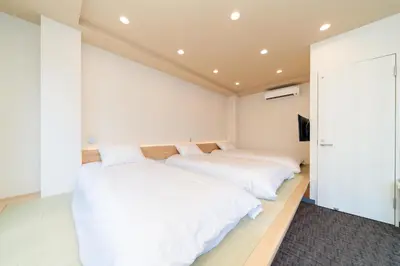 two beds in a room with white walls at Sunshine Inn 456 - Economic APT in Tokyo Tranquil Block, with Direct Access to Ginza & Akihabara in Tokyo