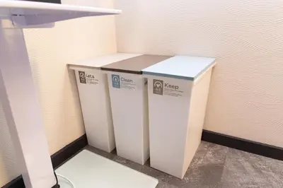 three white trash cans sitting next to a wall at Luum Stay Shibuya 2 in Tokyo
