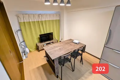 a room with a wooden table and a television at Arms Nishi-Shinjuku in Tokyo