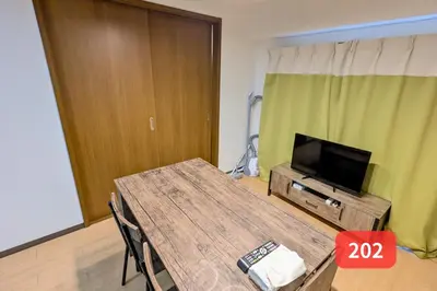 a living room with a table and a flat screen tv at Arms Nishi-Shinjuku in Tokyo