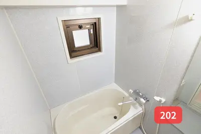 a small bathroom with a tub and a mirror at Arms Nishi-Shinjuku in Tokyo