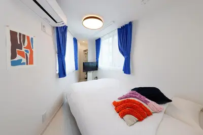 a small bedroom with a white bed and blue curtains at Lumiere de Zenith Shinagawa by Tranova in Tokyo