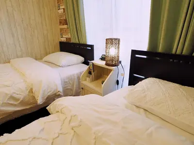 a bedroom with two beds and a lamp on a night stand at 202 Koiwa st private Room in Tokyo