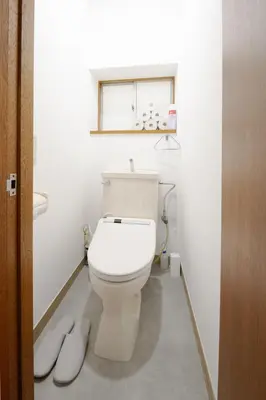 a bathroom with a toilet with a window and slippers at KASHIMA -JR Otsuka Station- in Tokyo