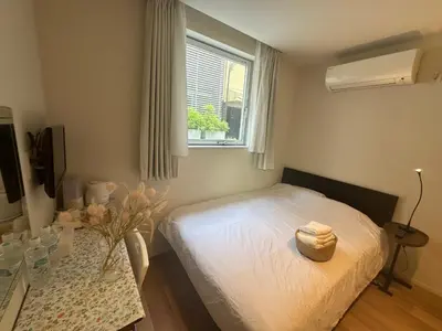 a bedroom with a bed and a table and a window at Ficus Tokyo in Tokyo