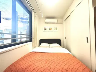a small bed in a room with a large window at ToyoHomes\u897f\u65b0\u5bbf in Tokyo