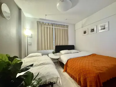 a bedroom with two beds and a table and a window at ToyoHomes\u897f\u65b0\u5bbf in Tokyo