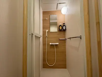 a bathroom with a shower with a hose on the wall at Nanayado Asakusa Okachimachi in Tokyo