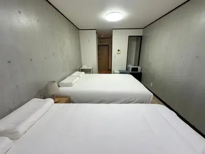two beds in a small room with two beds at West Shinjuku Nakano Family Inn in Tokyo
