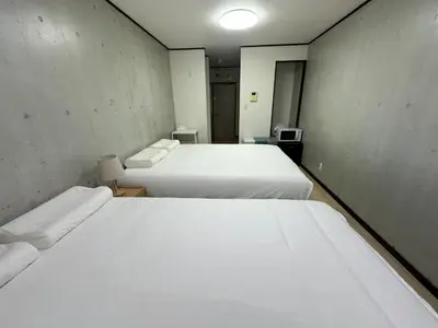 two beds in a room with white sheets at West Shinjuku Nakano Family Inn in Tokyo