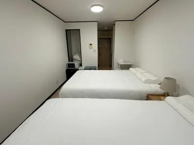 two beds in a room with white walls at West Shinjuku Nakano Family Inn in Tokyo