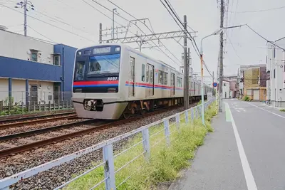 a train traveling down the tracks next to a street at SC 105 Cozy Private Stay with Loft Near Station Free WiFi in Tokyo