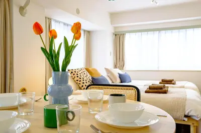 a living room with a table with a vase with orange flowers at Palaisgrace Shibuya - Live Like a Trendy Local in Sangenjaya \u4e09\u8ed2\u8336\u5c4b - Direct Shibuya Access in Tokyo