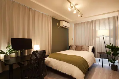 a bedroom with a bed and a desk with a computer at Shirogane Apartment in Tokyo